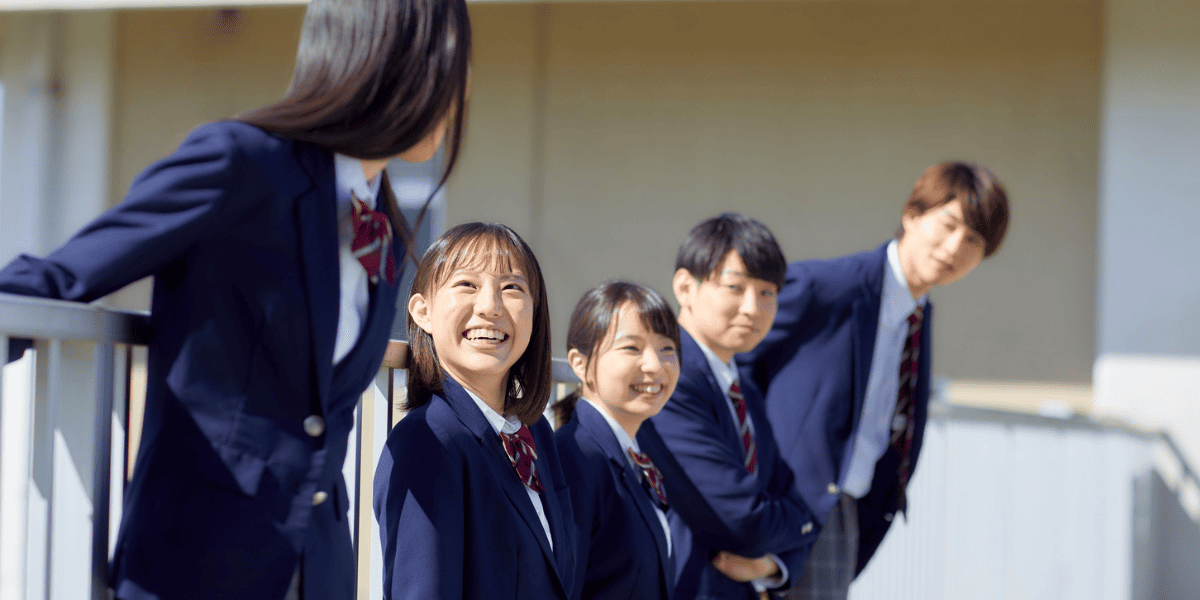 横に並んで屋外で笑いあう高校生たち