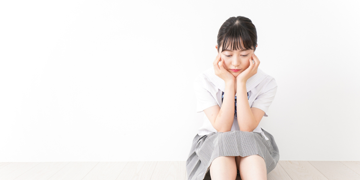 下を向いて悩んでいる女子高校生