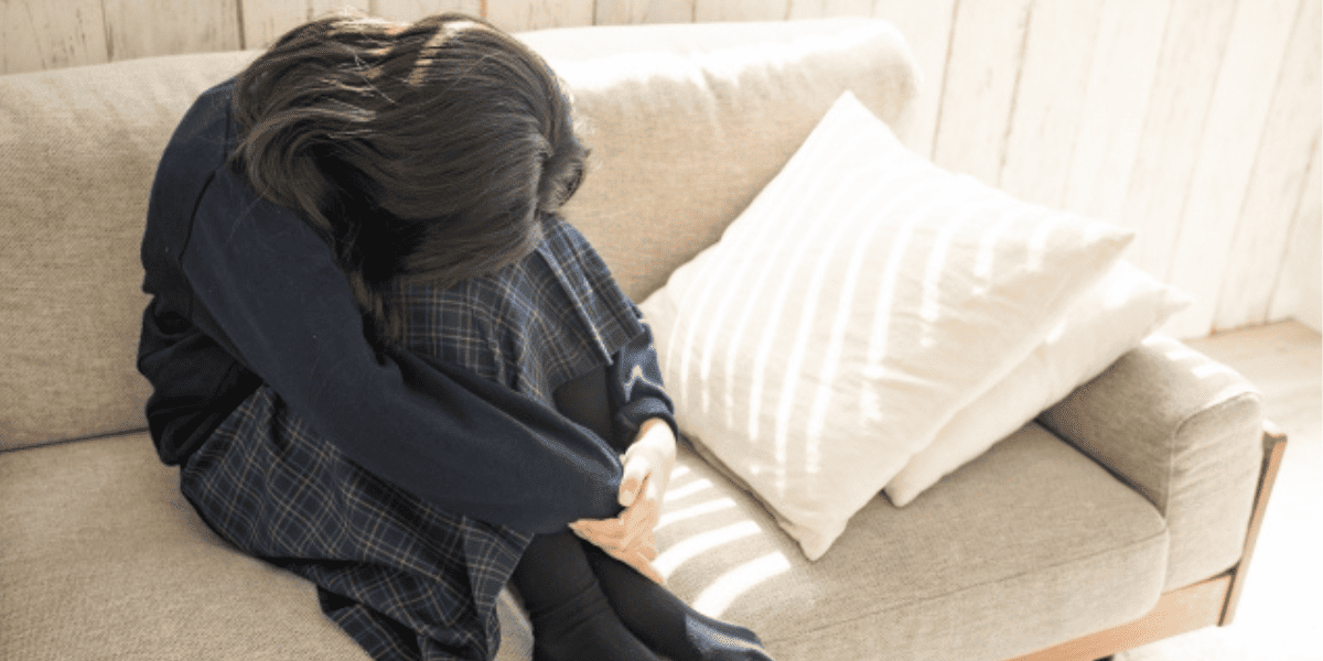 部屋でひざを抱える女子高生