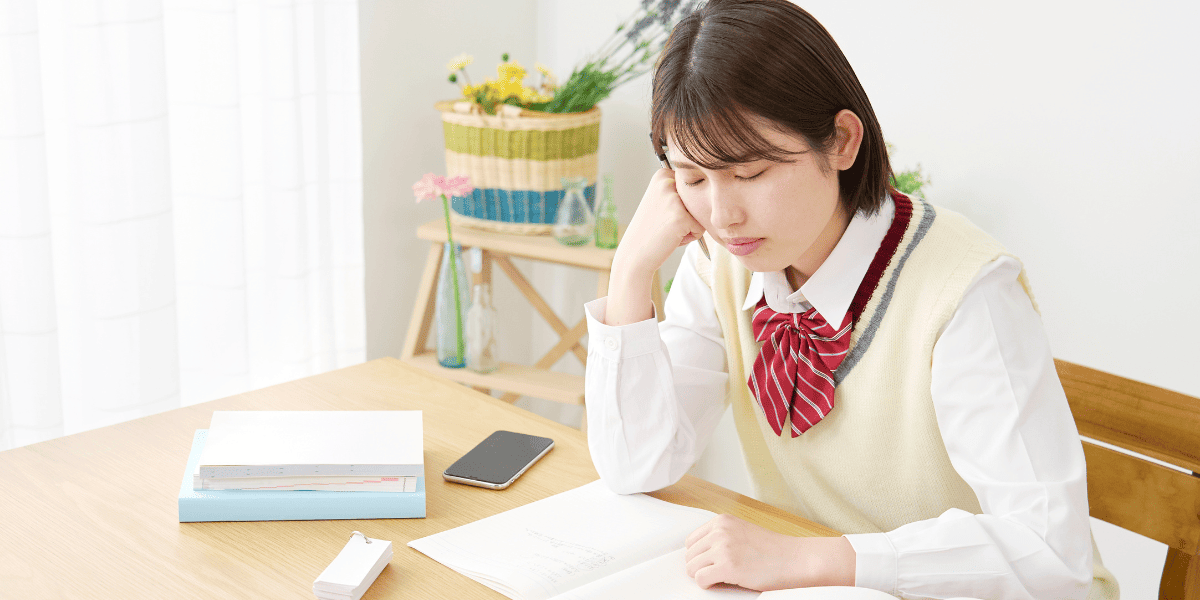 机で勉強しながらうとうとする女子高生