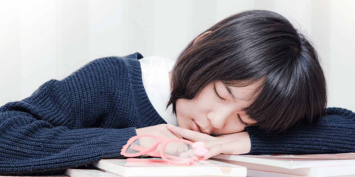 机に突っ伏して寝る女子高生