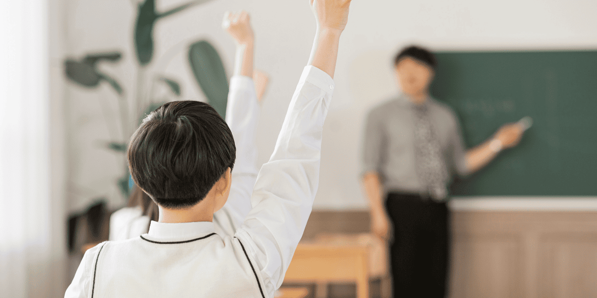 手を挙げて勉強する中学生