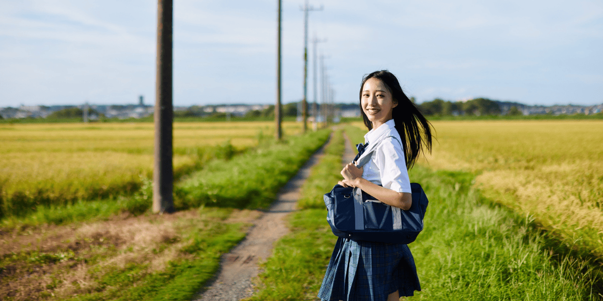 田んぼでこちらに微笑む中学生