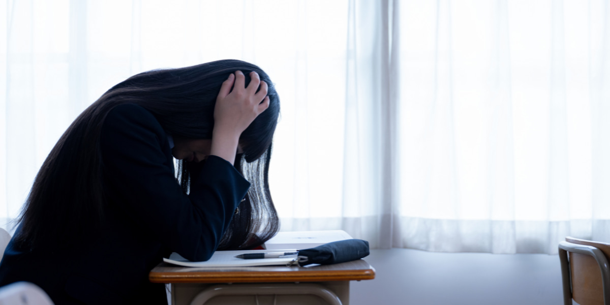 /upload/column/reasons-for-not-attending-school-01.jpg 教室で頭を抱えている女子中学生