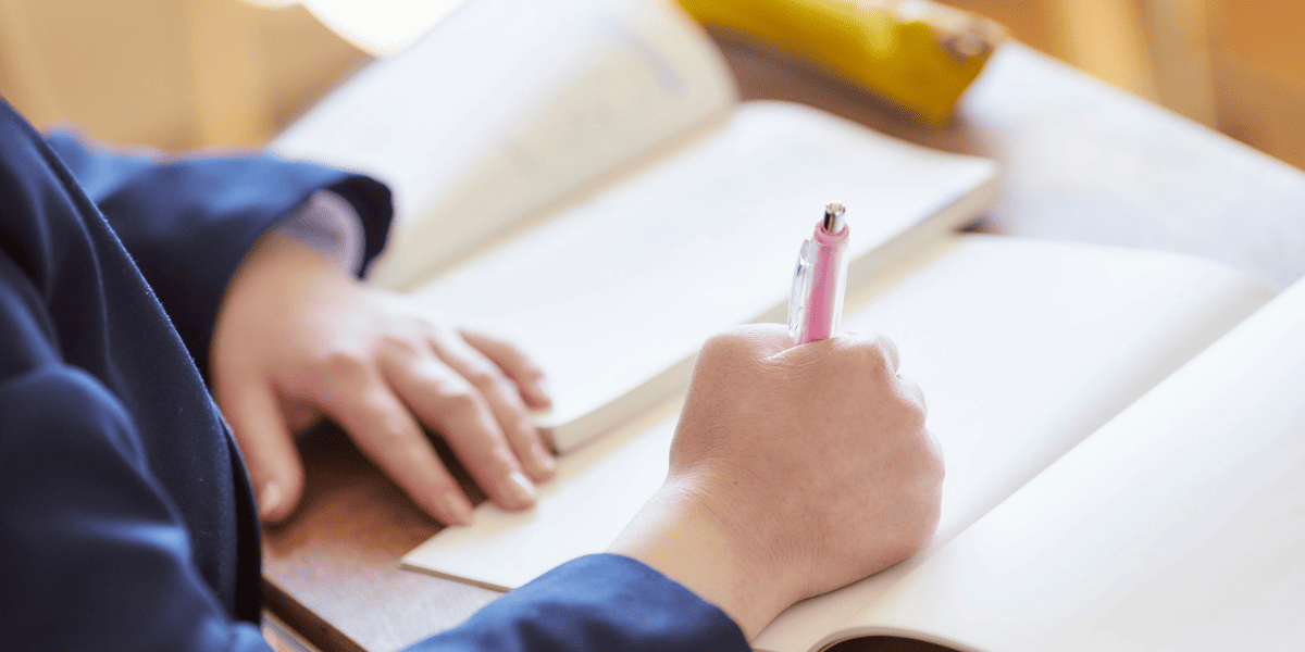 テキストを開いてノートに字を書く生徒