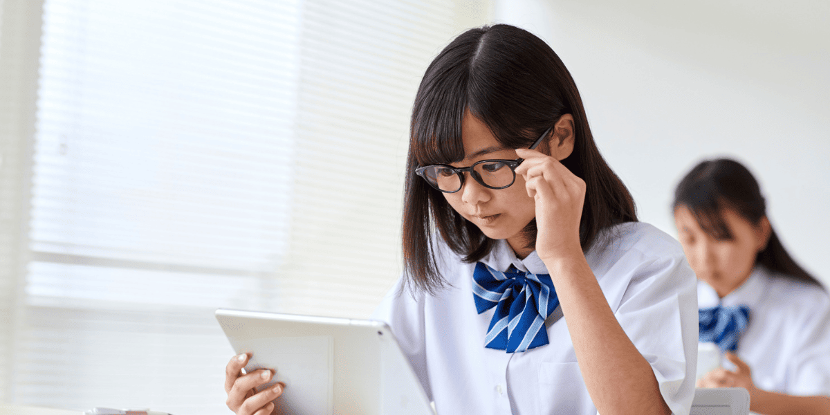 メガネをかけた少女が電子機器で勉強している