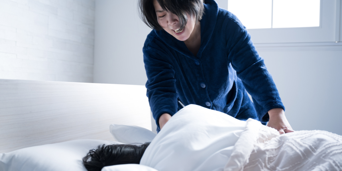 寝ている子供を起こしている母親
