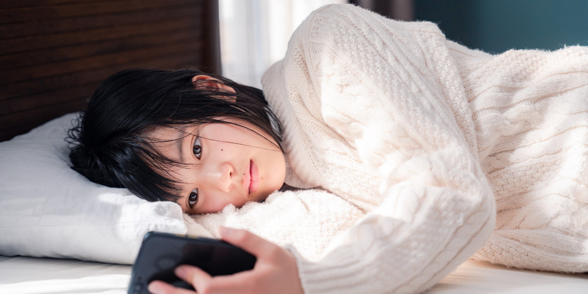 ベッドでスマホを見ている女性