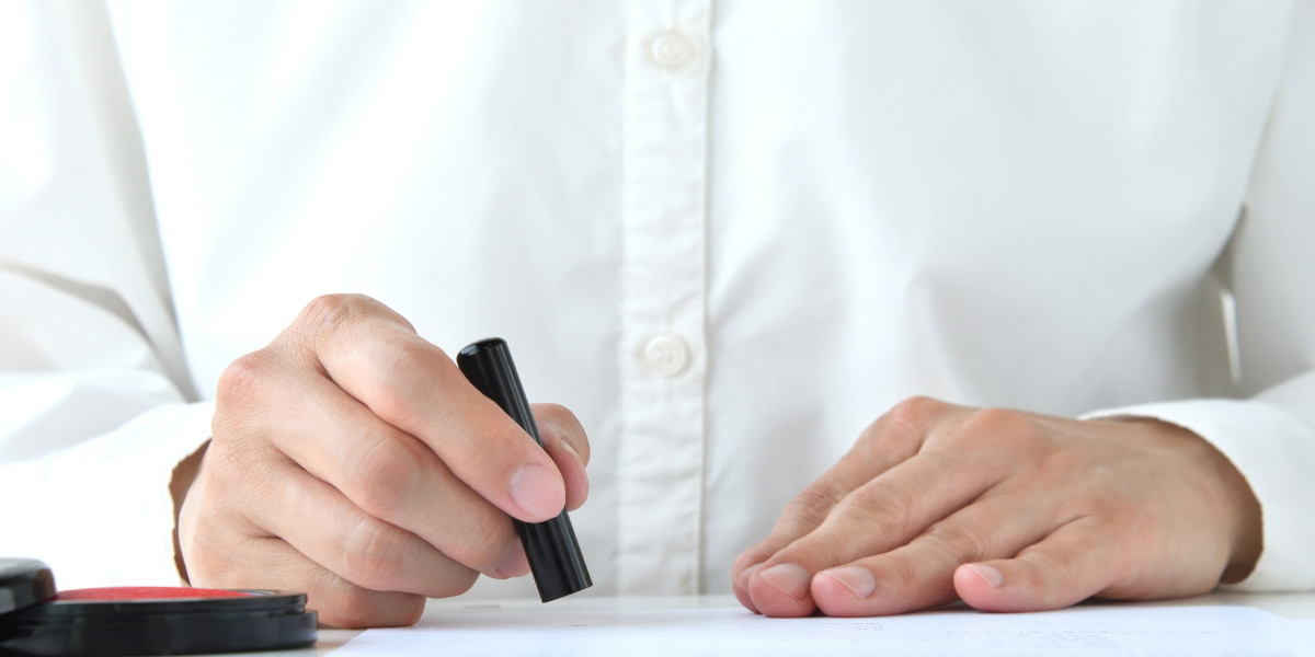 契約書にハンコを押している男性